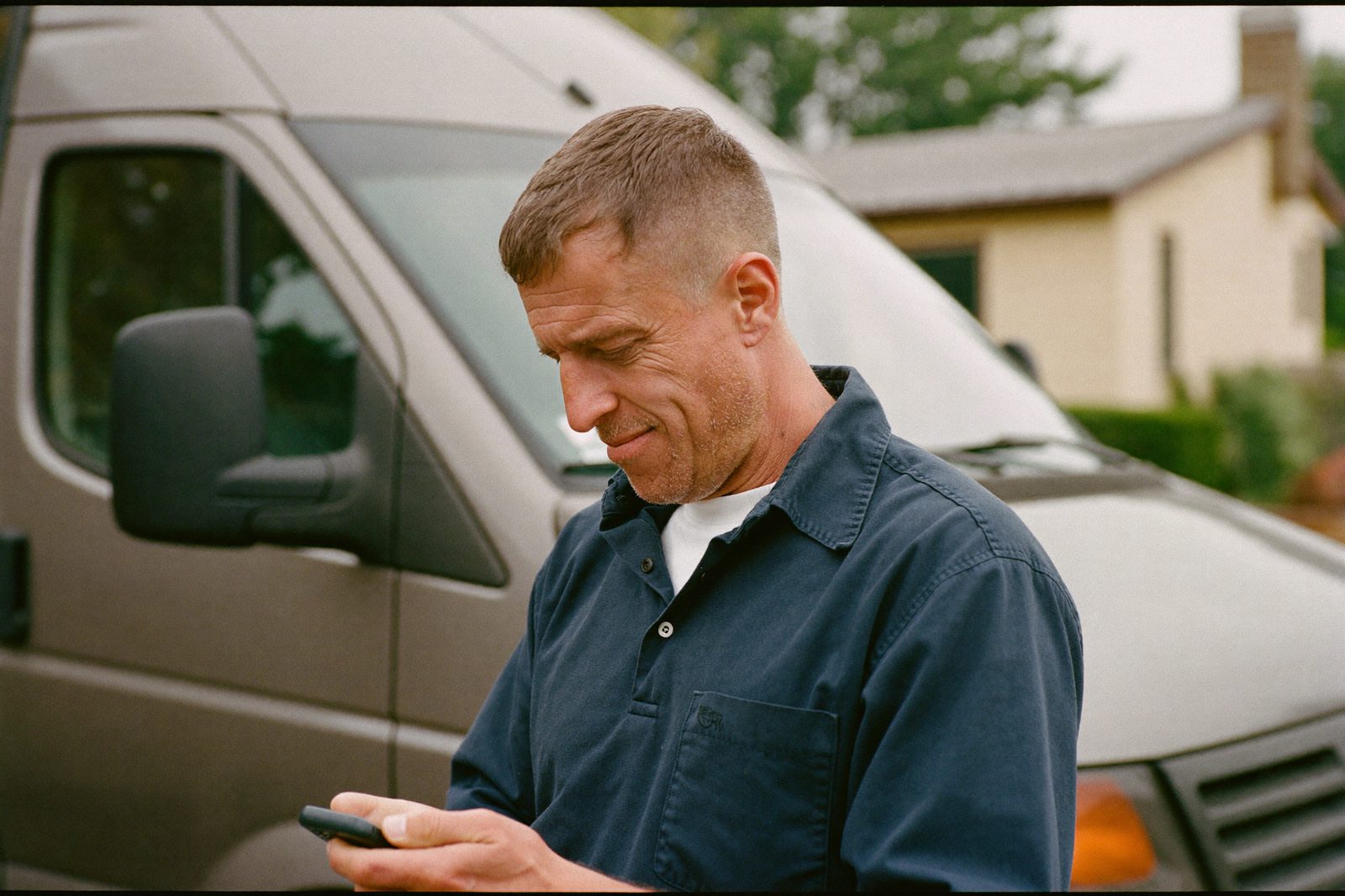 Local service business owner checking new job leads on his phone beside his work van